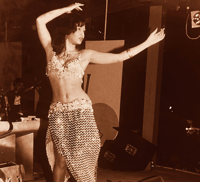 Photo d'époque d'Esther Mattar, danseuse et enseignante de baladi égyptien, dansant le baladi dans une pièce de spectacle, habillée de costume à paillettes.