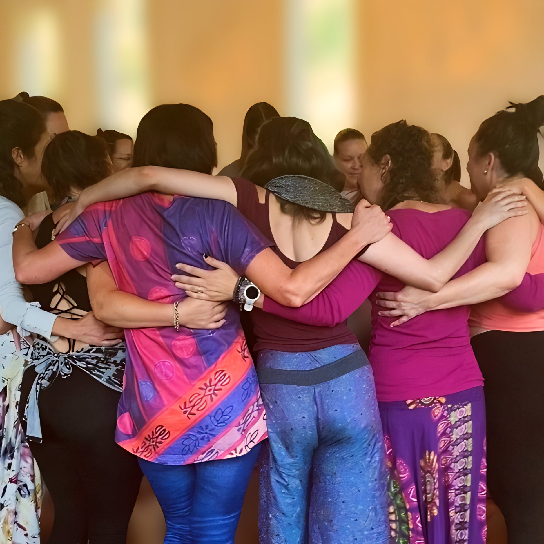 Groupe de femmes se tenant en cercle, serrées les unes contre les autres, s'enlaçant par les épaules.